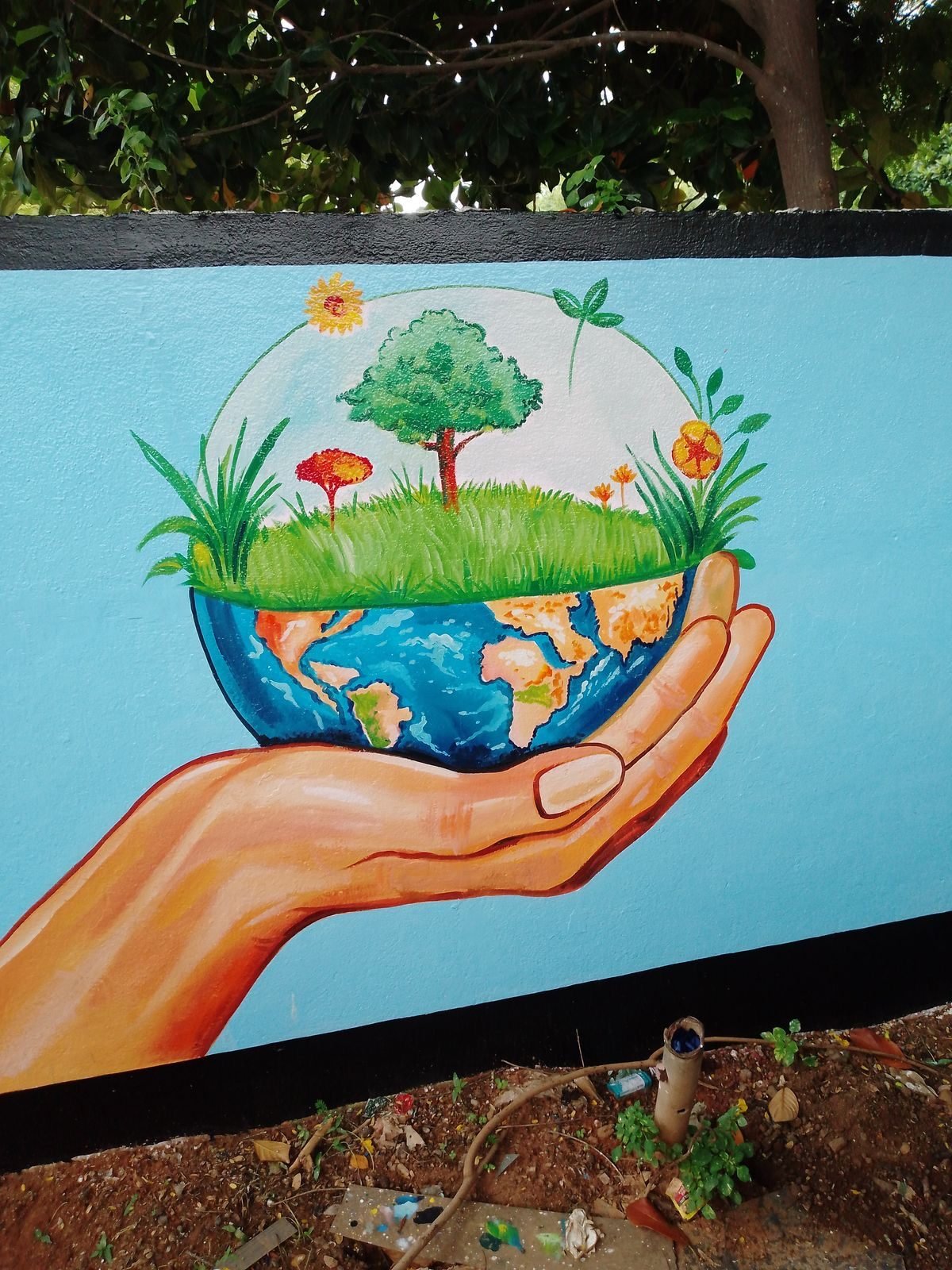 Colourful wall painting showing a hand holding earth and greenery